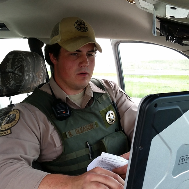 FWP Game warden working at a computer in his vehicle