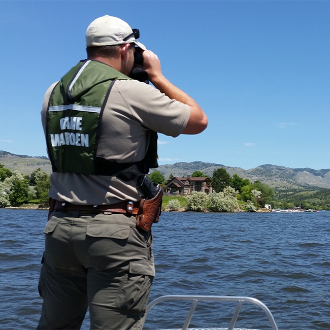 An FWP Warden using binoculars on the water