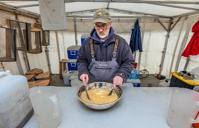 Hatchery volunteers use wild turkey feathers to mix a slurry of walleye eggs and milt.