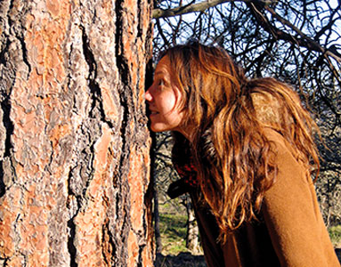 A woman smells a ponderosa pine.